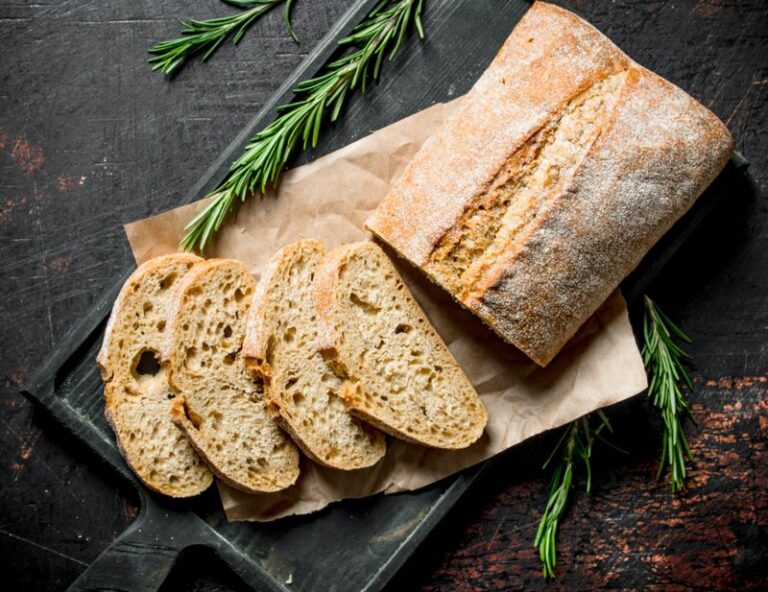 Sliced ciabatta bread on a cutting Board with rosemary